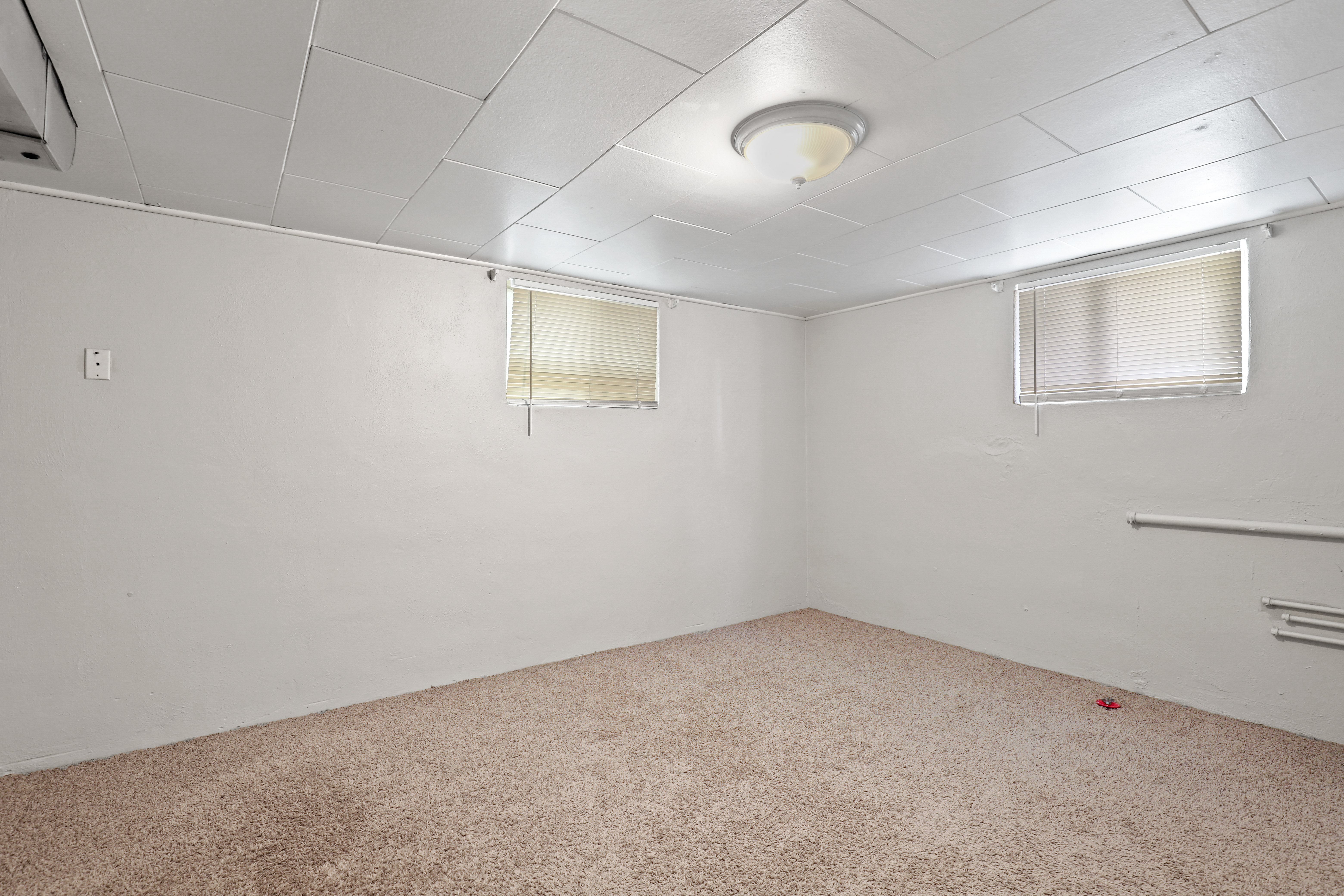 the interior of an empty room with carpet and two windows